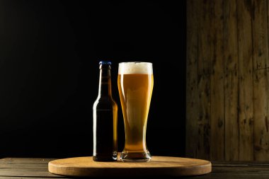 Dolu bir şişe ve ahşap masada yarım litre bira fotokopi alanı olan bir resim. Alkol, içecek ve bira günü kutlamaları..