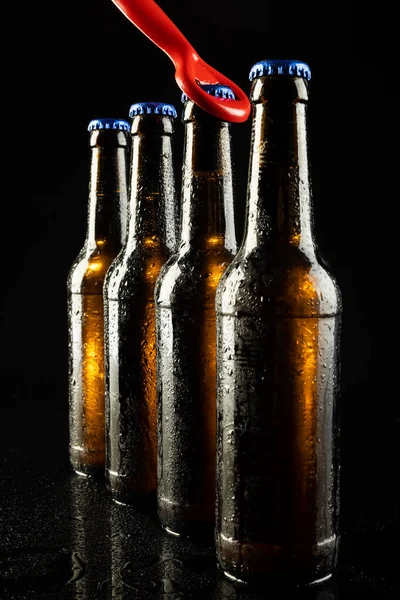 赤のボトルのオープナーと黒のコピースペースとブルークラウンキャップと4本のビールボトルのイメージ アルコール リフレッシュメント ラガーデーのお祝いのコンセプト — ストック写真
