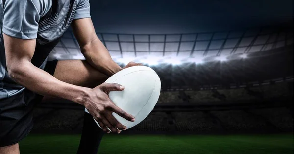 Composition of male rugby player holding rugby ball over sports stadium. sport and competition concept digitally generated image.