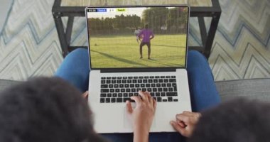İki Afrikalı Amerikalının kanepede oturup dizüstü bilgisayardan futbol maçı izlediği bir video. Futbol ve tezahürat kavramı.