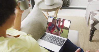 Kanepede oturup dizüstü bilgisayardan futbol maçı izleyen birinin videosu. Futbol ve tezahürat kavramı.