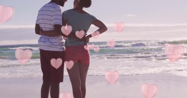 Animacja Różowych Serc Nad Szczęśliwą Afrykańską Parą Obejmującą Się Plaży — Wideo stockowe