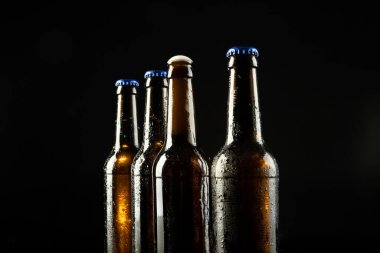 Dört bira şişesinin resmi. Biri diğerini mavi kapaklı, diğeriyse siyah kapaklı. Alkol, içecek ve bira günü kutlamaları..