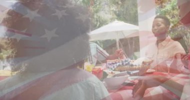Afro-Amerikan ailesinin yemek yemesi üzerine Amerikan bayrağının animasyonu. Küresel vatanseverlik ve dijital arayüz kavramı dijital olarak oluşturulmuş video.