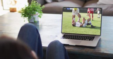 Kanepede oturup dizüstü bilgisayardan futbol maçı izleyen birinin videosu. Futbol ve tezahürat kavramı.