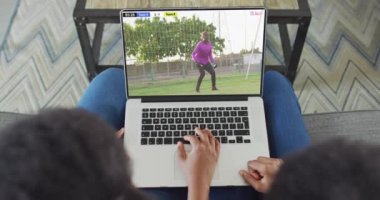 İki Afrikalı Amerikalının kanepede oturup dizüstü bilgisayardan futbol maçı izlediği bir video. Futbol ve tezahürat kavramı.