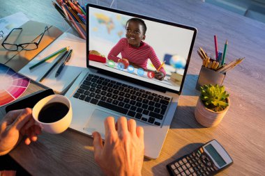 Erkek öğretmenle video görüşmesi sırasında dizüstü bilgisayardan öğrenen Afrikalı Amerikalı kız öğrenci. Çevrimiçi eğitim karantina süresince evde tek başına kalıyor..