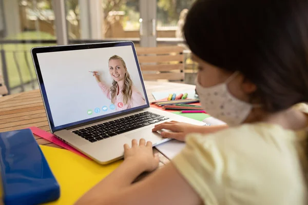 在学校 戴着面具的女学生在笔记本电脑上与女教师进行视频通话 Covid 19概念期间的在线远程教育 — 图库照片