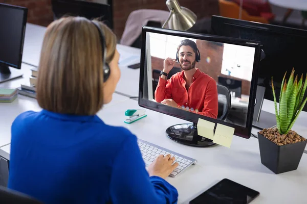 사업가가 책상에 앉아서 컴퓨터로 동료와 비디오 통화를 있습니다 현대식 사무실에서 — 스톡 사진