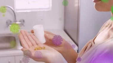 Yüzen renkli Covid-19 hücrelerinin animasyonu. Beyaz kadının evinde hap içmesi üzerine. Covid-19 Coronavirus salgını sırasında tıbbi personel.