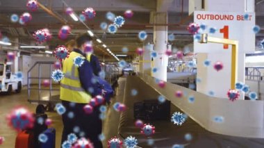 Yüzen makro Covid-19 hücrelerinin iki beyaz erkek havaalanı işçisinin bagaj yerleştirmesi. Toplu taşıma Covid-19 koronavirüs salgını sırasında sosyal mesafeyle yeniden açılıyor.