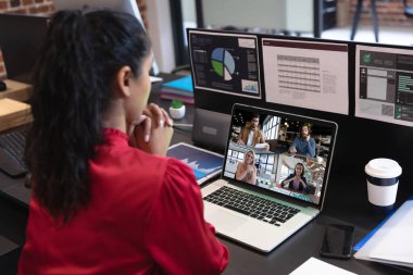 Beyaz bir kadın laptopta çeşitli meslektaşlarıyla görüntülü görüşme yapıyor. Covid 19 salgını sırasında sosyal mesafeli iletişim teknolojisi işyeri.