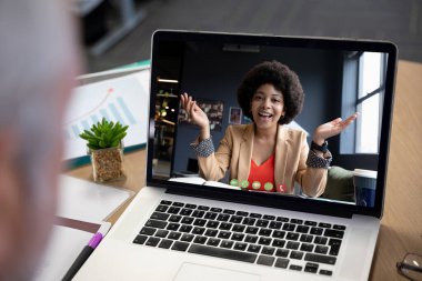 Ofis video görüşmesi sırasında dizüstü bilgisayarda gösterilen gülümseyen karışık ırk iş kadını. Covid 19 salgını sırasında sosyal mesafeli iletişim teknolojisi işyeri.