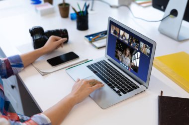 Beyaz bir kadın laptopta çeşitli meslektaşlarıyla görüntülü görüşme yapıyor. Covid 19 salgını sırasında sosyal mesafeli iletişim teknolojisi işyeri.