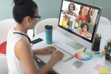 Beyaz bir kadın öğretmen okulda bilgisayar başında birden fazla öğrenciyle video konferansı yapıyor. uzak öğrenim çevrimiçi eğitim kavramı