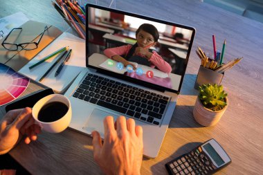 Öğretmenin, kız öğrenciyle okulda bilgisayar başında görüntülü konuşma yapması. uzak öğrenim çevrimiçi eğitim kavramı