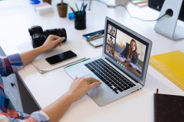 Beyaz bir kadın laptopta çeşitli meslektaşlarıyla görüntülü görüşme yapıyor. Covid 19 salgını sırasında sosyal mesafeli iletişim teknolojisi işyeri.