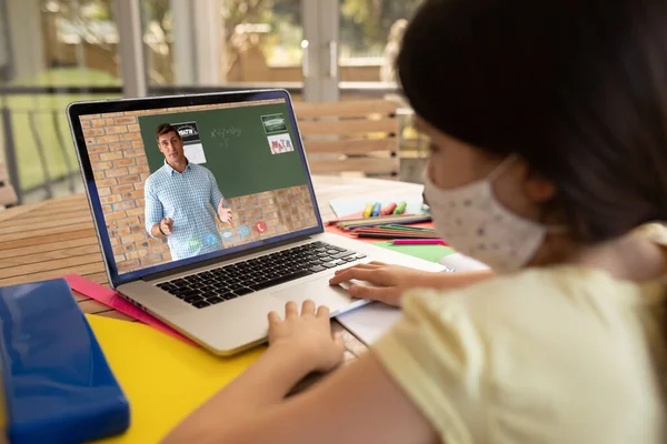 在学校 戴着面具的女学生在笔记本电脑上与男教师进行视频通话 Covid 19概念期间的在线远程教育 — 图库照片