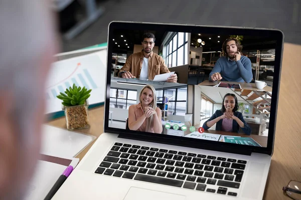 Diverse business people displayed on laptop screen during office video call. social distancing communication technology workplace during covid 19 pandemic.