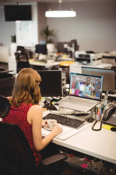 ノートパソコンを使って机に座っている白人の実業家はビデオ通話をしている 近代的なオフィスで働いていて — ストック写真