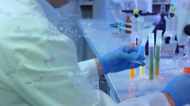 Örnekleri kontrol eden ve laboratuvarda dizüstü bilgisayar kullanan bir grup etnik doktor üzerinde yüzen matematiksel denklemlerin animasyonu. Covid-19 Coronavirus salgını sırasında tıbbi personel.