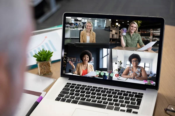 Diverse businesswomen displayed on laptop screen during office video call. social distancing communication technology workplace during covid 19 pandemic.