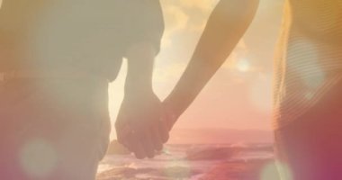 Sahilde el ele tutuşan ve hipnotik hareketlerle hareket eden birden fazla parlak ışık noktasıyla yürüyen çiftin orta bölümünün animasyonu. Rahatlatıcı ve sakin konsept dijital olarak oluşturulmuş görüntü.