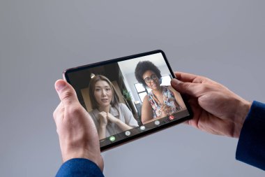 İş adamlarının elleri, dijital tablet kullanan çok ırklı kadın iş arkadaşlarıyla görüntülü konferans yapıyor. Değiştirilmemiş, toplantı, takım çalışması, ofis, iletişim ve teknoloji kavramı.