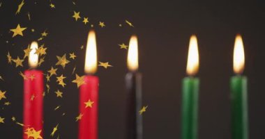 Kwanzaa mumlarının üzerine siyah arka planda düşen altın yıldızların animasyonu. Kwanzaa şenliği, kutlama ve gelenek konsepti dijital olarak oluşturulmuş video.