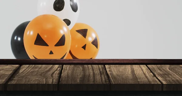 Image of halloween text over halloween balloons on wooden background. Halloween, autumn, fall, festivity tradition and celebration concept digitally generated image.