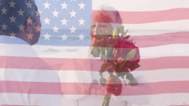 Amerika Birleşik Devletleri bayrağının animasyonu plajda sarılan yaşlı çiftler üzerine. Amerikan vatanseverliği, çeşitlilik ve gelenek konsepti dijital olarak oluşturulmuş video.