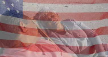 Amerika Birleşik Devletleri bayrağının sahildeki güverte sandalyelerinde üst düzey melez çiftler üzerinde canlandırılması. Amerikan vatanseverliği, çeşitlilik ve gelenek konsepti dijital olarak oluşturulmuş video.
