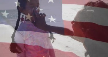 Amerika Birleşik Devletleri bayrağının animajı, kumsalda kızı olan melez bir anne yerine. Amerikan vatanseverliği, çeşitlilik ve gelenek konsepti dijital olarak oluşturulmuş video.
