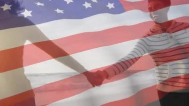 Amerika Birleşik Devletleri bayrağının deniz kenarında el ele tutuşan melez bir çift üzerinde canlandırılması. Amerikan vatanseverliği, çeşitlilik ve gelenek konsepti dijital olarak oluşturulmuş video.