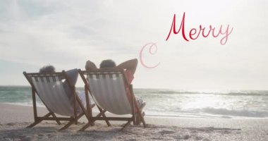 Sahildeki üst düzey melez çiftin mutlu noel mesajlarının animasyonu. Noel, gelenek ve kutlama konsepti dijital olarak oluşturuldu.