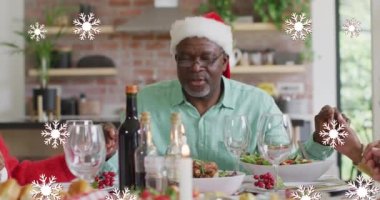 Beyaz kar tanelerinin farklı kıdemli arkadaşlarla yılbaşı yemeğinde dua etmesinin animasyonu. Noel, tatiller, şenlik, gelenek ve dijital olarak üretilen kutlama konsepti.