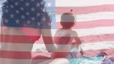 Amerika Birleşik Devletleri bayrağının deniz kenarında çocuklu melez çiftler üzerinde canlandırılması. Amerikan vatanseverliği, çeşitlilik ve gelenek konsepti dijital olarak oluşturulmuş video.