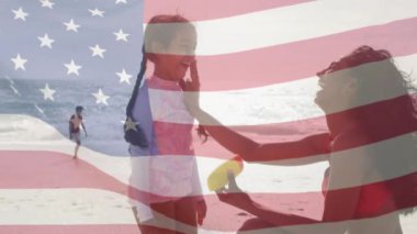 Amerika Birleşik Devletleri bayrağının deniz kenarında çocuklu melez çiftler üzerinde canlandırılması. Amerikan vatanseverliği, çeşitlilik ve gelenek konsepti dijital olarak oluşturulmuş video.