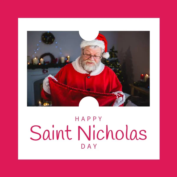 Composition of saint nicholas day text over santa claus holding red sack. Saint nicholas day, christmas festivity, tradition and celebration concept.
