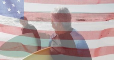 Amerika Birleşik Devletleri bayrağının sahilde sörf yapan yaşlı çiftler üzerinde canlandırılması. Amerikan vatanseverliği, çeşitlilik ve gelenek konsepti dijital olarak oluşturulmuş video.