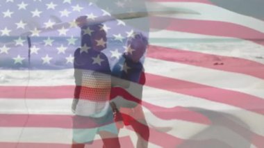Amerika Birleşik Devletleri bayrağının sahilde sörf yapan yaşlı çiftler üzerinde canlandırılması. Amerikan vatanseverliği, çeşitlilik ve gelenek konsepti dijital olarak oluşturulmuş video.