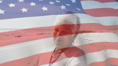 Amerika Birleşik Devletleri bayrağının sahildeki yaşlı melez kadın üzerinde canlandırılması. Amerikan vatanseverliği, çeşitlilik ve gelenek konsepti dijital olarak oluşturulmuş video.