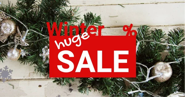 Composition of huge winter sale text over christmas decoration in background. Christmas, sales, tradition, celebration and festivity concept digitally generated image.