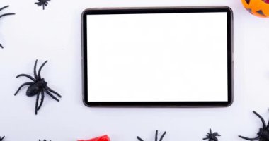 Beyaz arkaplanda örümcek ve tablet animasyonu. Cadılar bayramı, sonbahar, kutlama ve geleneksel konsept dijital olarak oluşturulmuş video.