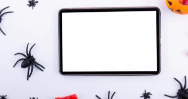 Beyaz arkaplanda örümcek ve tablet animasyonu. Cadılar bayramı, sonbahar, kutlama ve geleneksel konsept dijital olarak oluşturulmuş video.