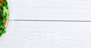 Yüksek açılı kesilmiş cam kasede taze sebze salatası ahşap masanın üzerinde, kopyalama alanı. Değiştirilmemiş, veganlık, organik, yiyecek, sağlıklı, destek, vegan günü ve kutlama konsepti.