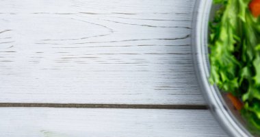 Ahşap masada cam kâse içinde sebze salatası, kopyalama alanı. Doğrudan yukarıda, değiştirilmemiş, veganlık, organik, yiyecek, sağlıklı, destek, vegan günü ve kutlama konsepti.