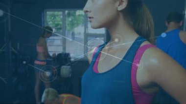 Spor kıyafetleri içinde bir kadın spor salonunda duruyor, dijital bağlantılarla çevrili..