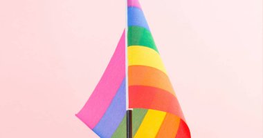 Gökkuşağı bayrağının yakın plan görüntüsü, pembe arka plan, kopyalama alanı. Değiştirilmemiş, lgbtqia hakları, kutlama, özgürlük, eşitlik, kimlik, farkındalık ve gurur kavramı.