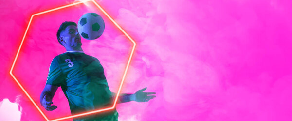 Caucasian male player balancing ball on chest over illuminated hexagon shape against pink background. Copy space, digital composite, sport, soccer, competition, neon, smoke, glowing and abstract.